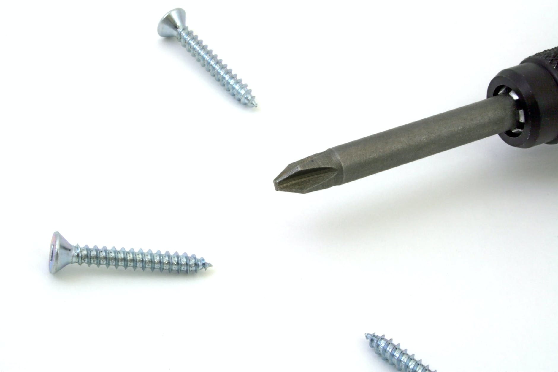 A screwdriver tip surrounded by screws.