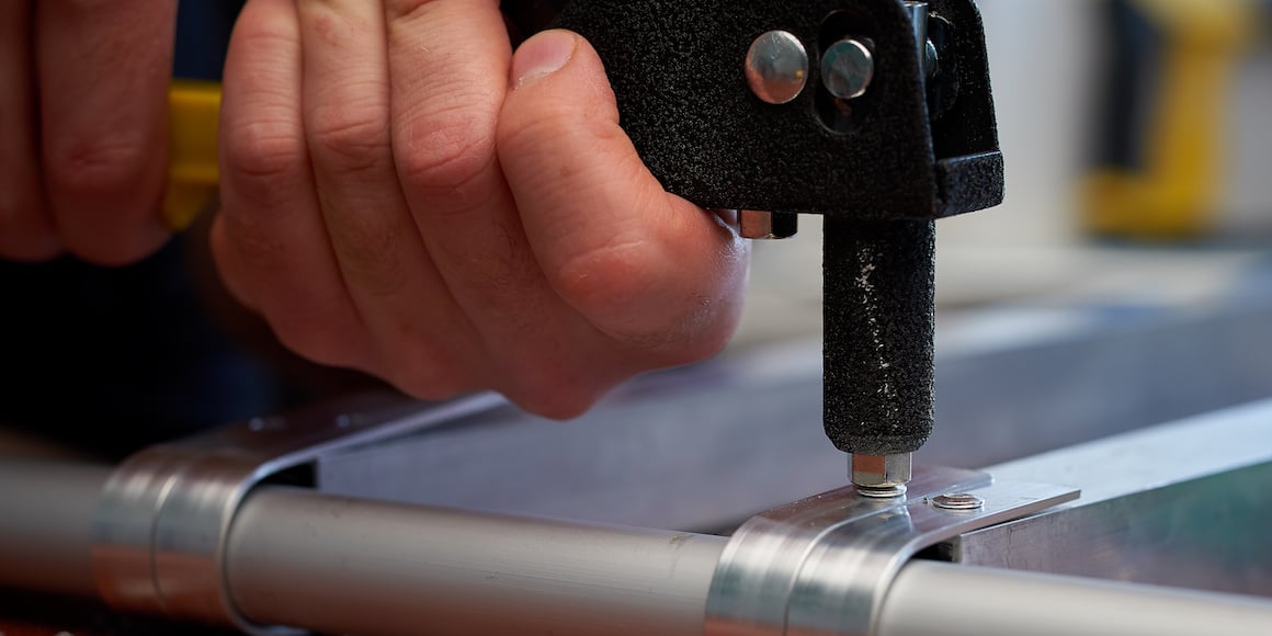 Man using a riveter to install rivets into an aluminum base